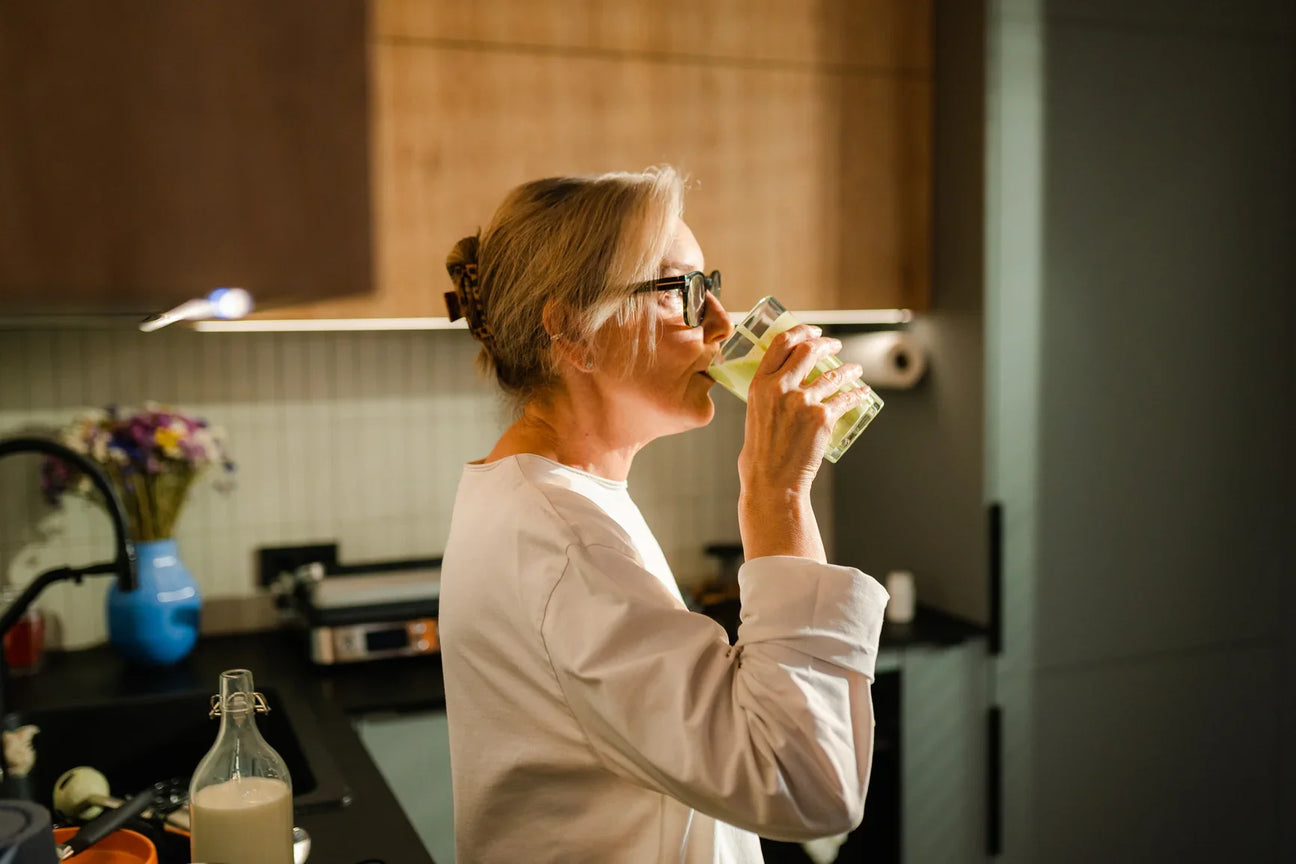 woman drinking out of glass in kitchen